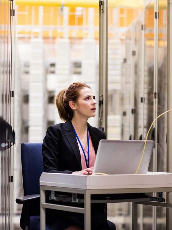 Technician using laptop while analyzing server in server room